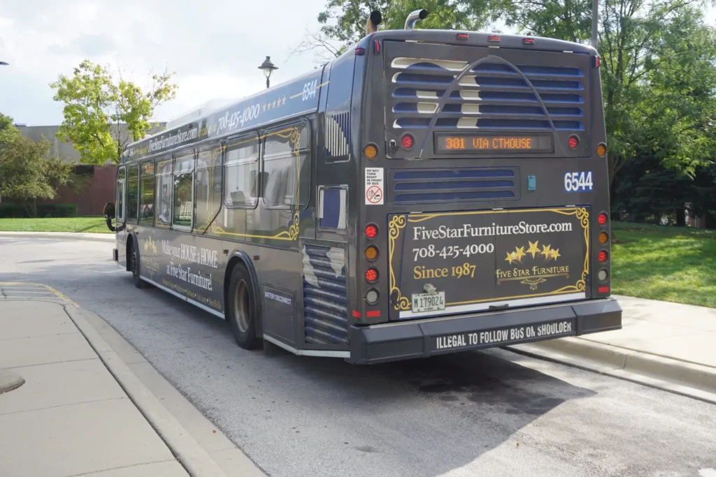 A fully wrapped Pace bus with Five Star Furniture's advertising on both sides and the back. The bus is pulling up to the sidewalk and the rear advertisement is easily seen.