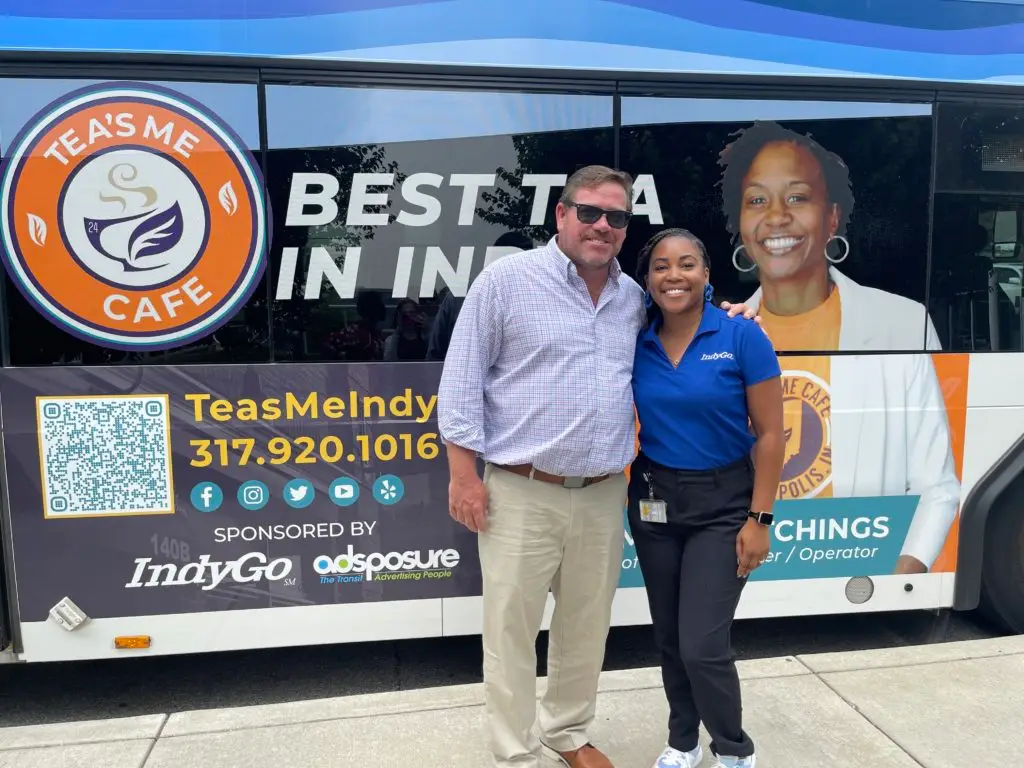 Jason Klare, left, pictured with Lesley Gordon, right. Jason and Lesley are standing in front of an IndyGo bus with an advertisement on it for Tea's Me Cafe.